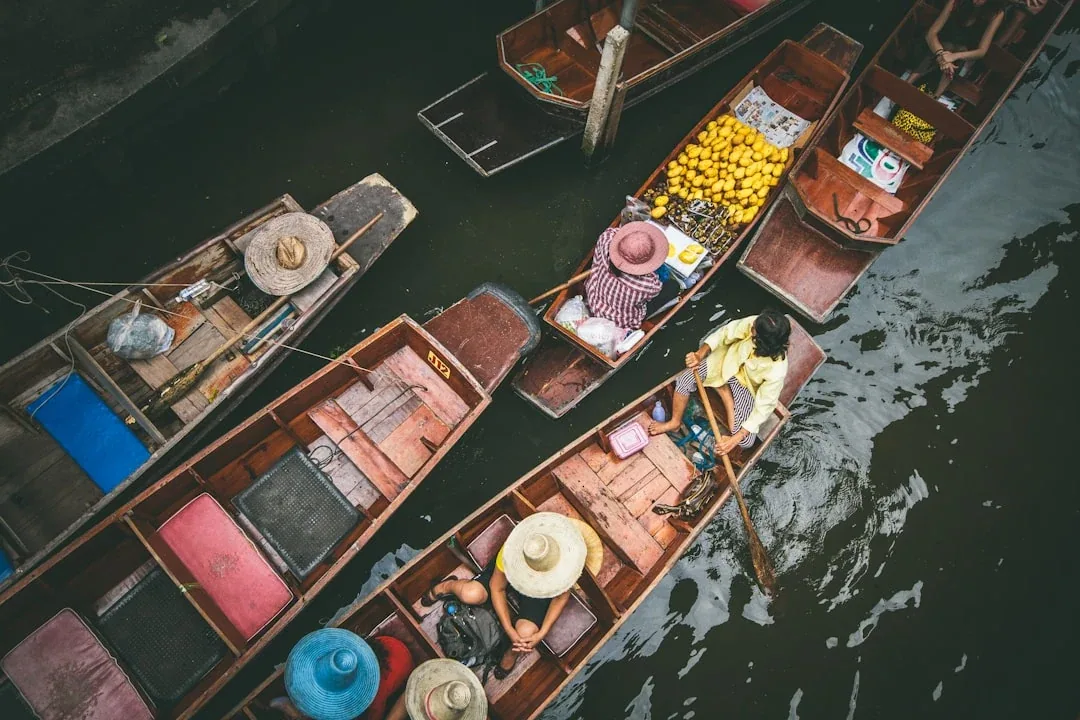 Overhead view of traditional wooden boats with vendors and tourists at Damnoen Saduak Floating Market in Ratchaburi, Thailand.
