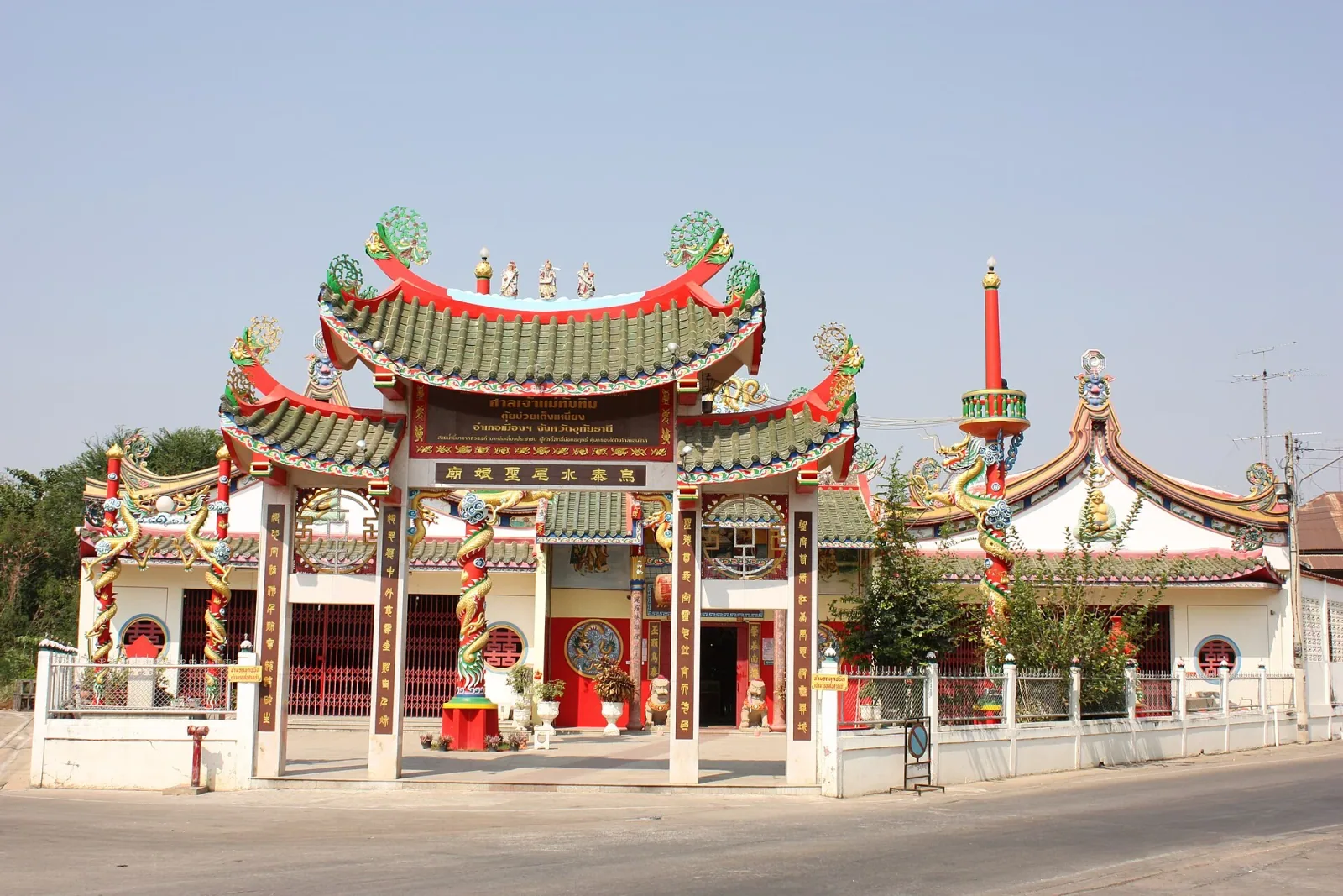 Exterior view of the colorful Hainanese Temple (Thap Thim Shrine) in Uthai Thani, featuring an ornate red, green, and gold gate with traditional Chinese architectural details.